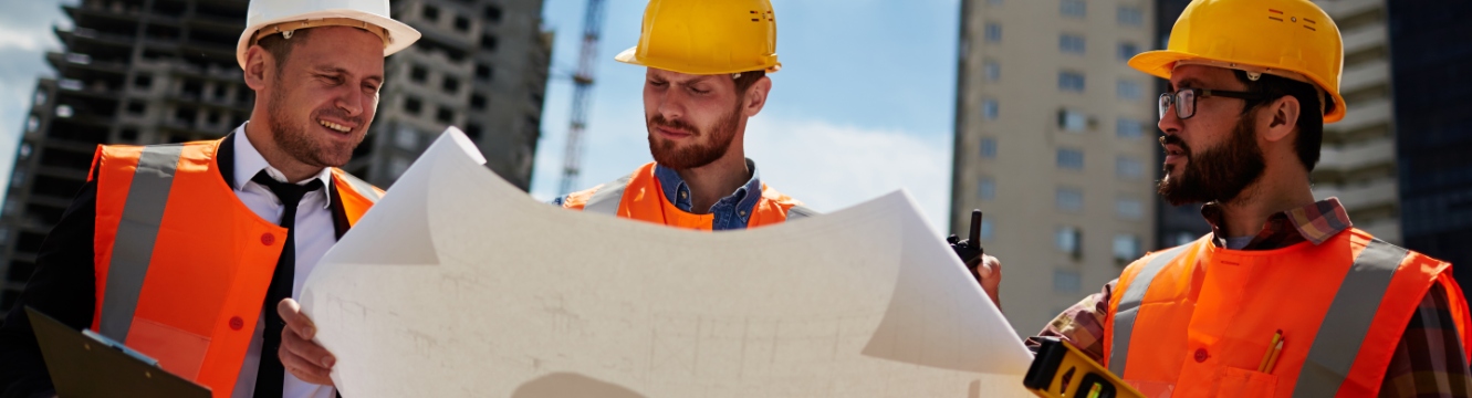 Trois personnes regardent un plan sur un chantier 